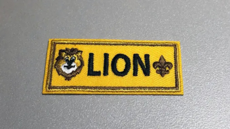 The Lion Rank Badge, the newest addition to Cub Scouts, is positioned directly below the left pocket under the Tiger badge